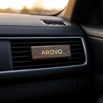 AROVO Diffusor am Lüftungsgitter eines Autos — mit 8,2 cm Länge dezent auf der Lamelle, dunkler Innenraum bei Abendlicht